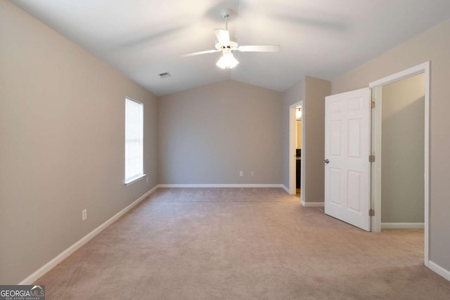 unfurnished bedroom featuring ceiling fan, light colored carpet, visible vents, vaulted ceiling, and baseboards