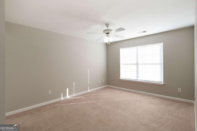 spare room featuring light carpet, baseboards, a ceiling fan, and visible vents