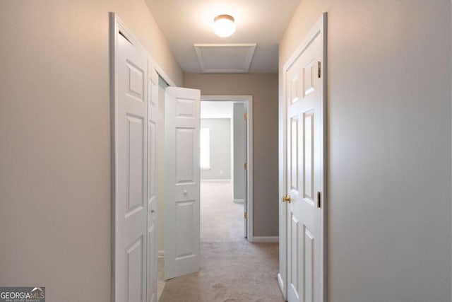 hallway featuring light carpet and baseboards