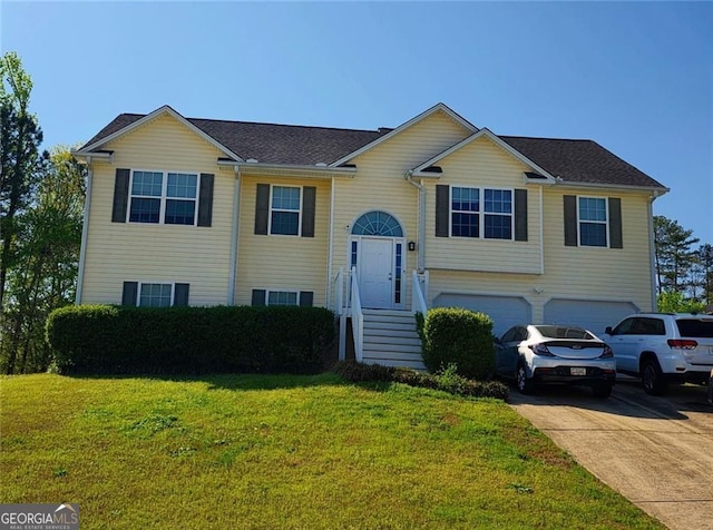 bi-level home with driveway, an attached garage, and a front lawn