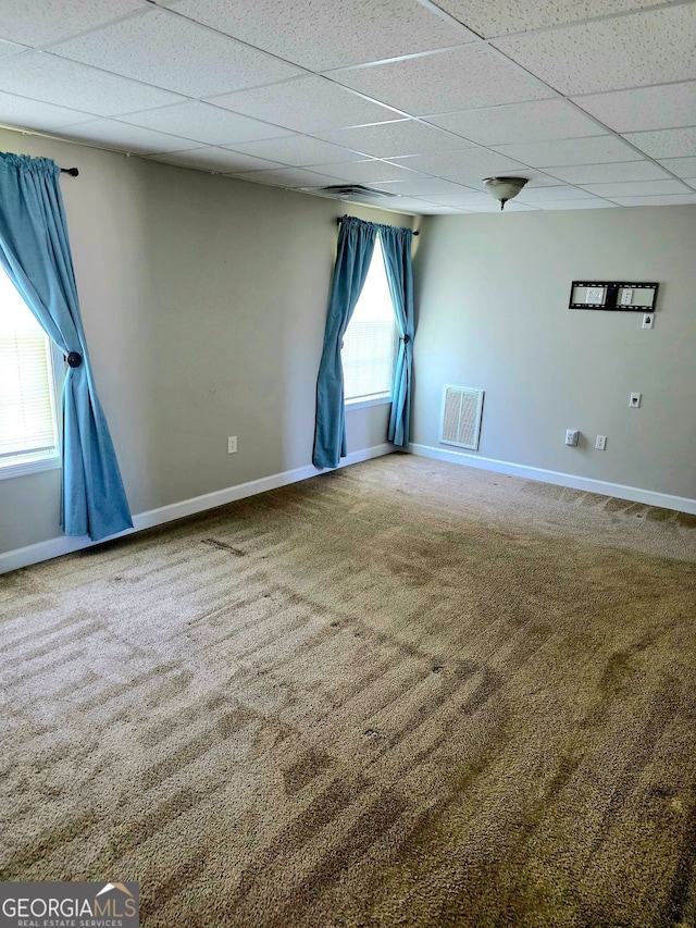 carpeted spare room with a paneled ceiling, baseboards, and visible vents
