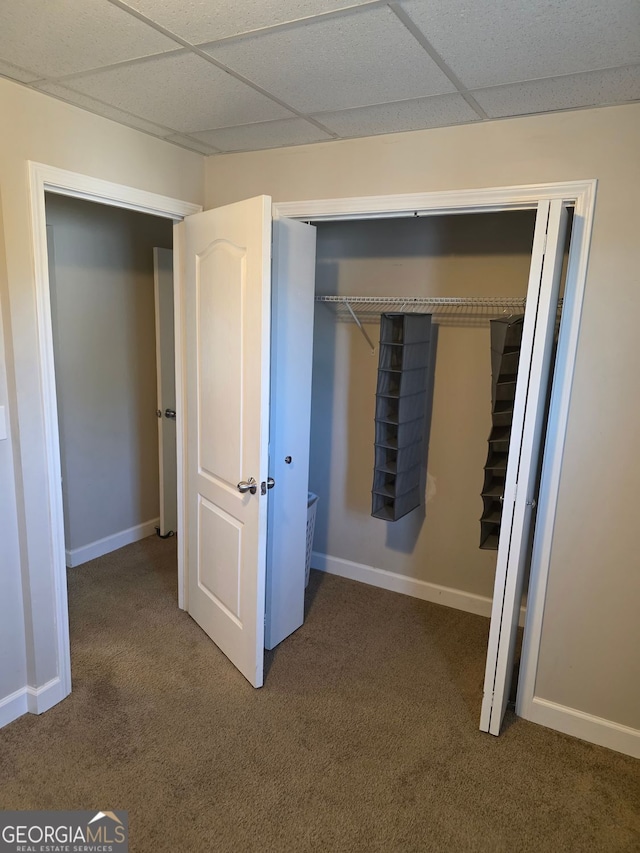 unfurnished bedroom featuring carpet floors, baseboards, and a drop ceiling