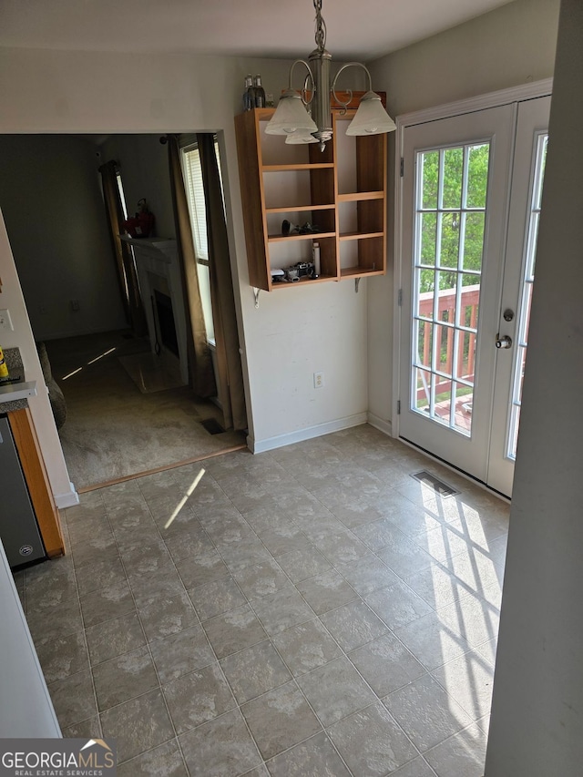 unfurnished dining area featuring a notable chandelier, visible vents, and baseboards