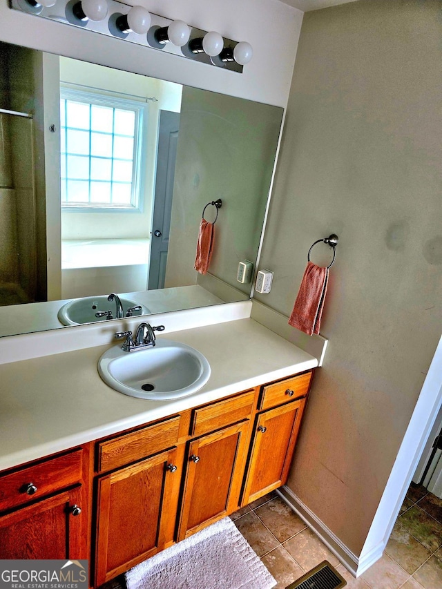 bathroom featuring visible vents, a bath, baseboards, vanity, and tile patterned flooring