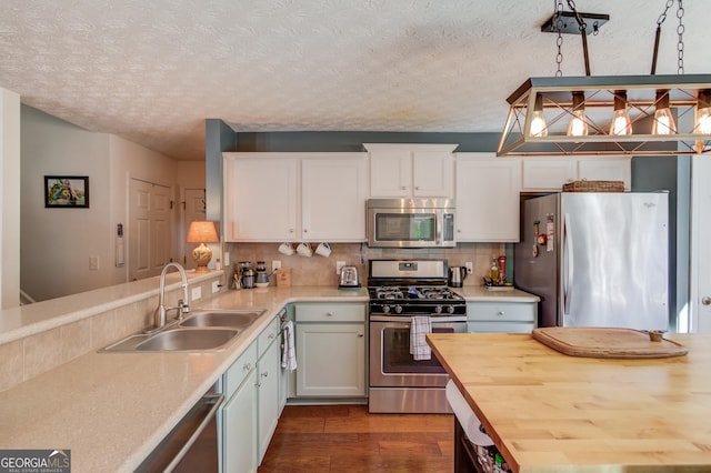 kitchen featuring white cabinetry, a sink, stainless steel appliances, dark wood-style floors, and backsplash