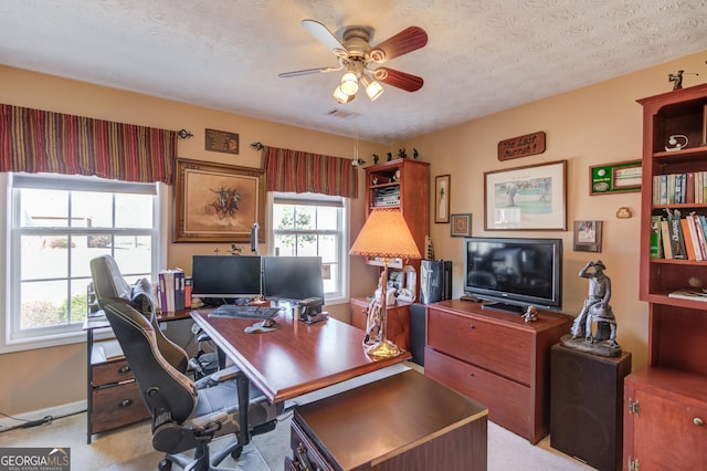 office area featuring a ceiling fan, visible vents, a textured ceiling, and baseboards