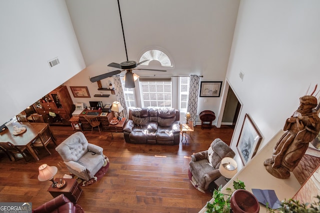 living room with visible vents, ceiling fan, wood-type flooring, and a towering ceiling