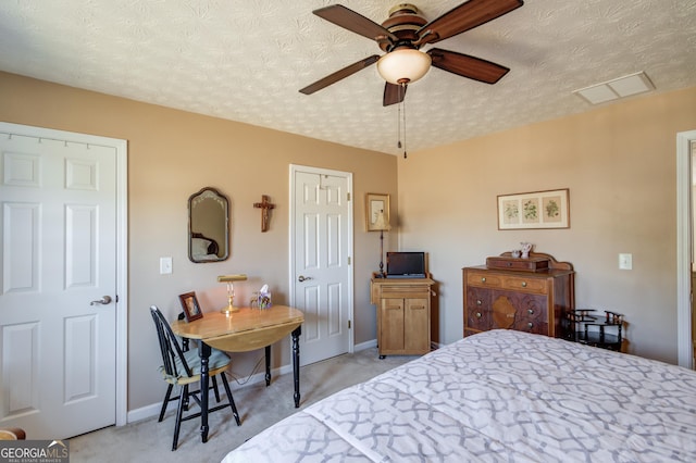 bedroom featuring a textured ceiling, visible vents, baseboards, and light carpet