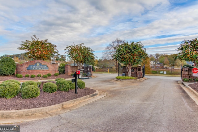 view of road with curbs, a gate, traffic signs, and a gated entry