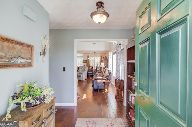 foyer with dark wood finished floors, a chandelier, and baseboards