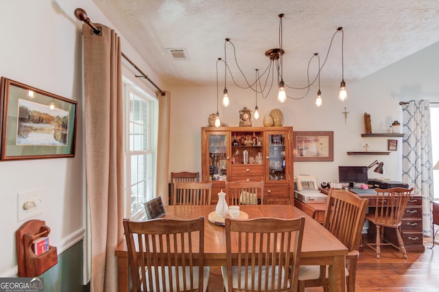 dining room with a textured ceiling, wood finished floors, and visible vents