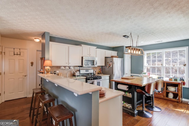 kitchen with stainless steel appliances, a textured ceiling, dark wood-style flooring, and light countertops