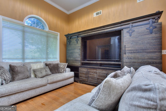 living area featuring wood finished floors, ornamental molding, and visible vents
