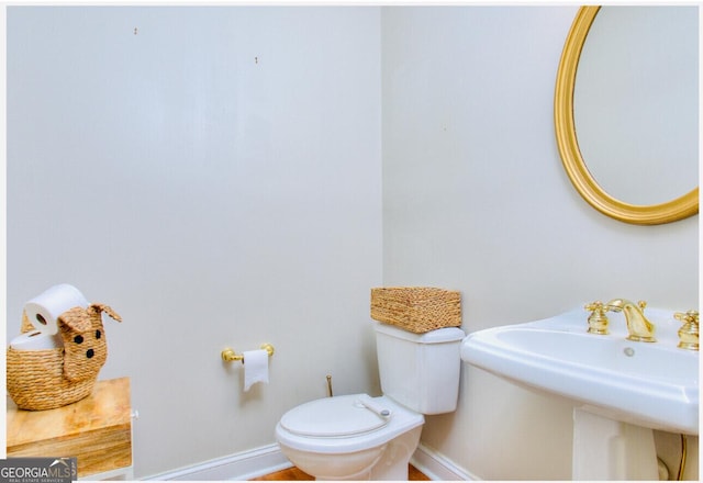 half bathroom featuring toilet, a sink, and baseboards