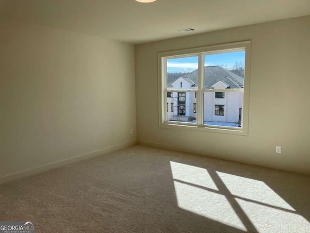 spare room featuring carpet flooring, baseboards, and visible vents
