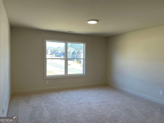 carpeted empty room featuring visible vents and baseboards