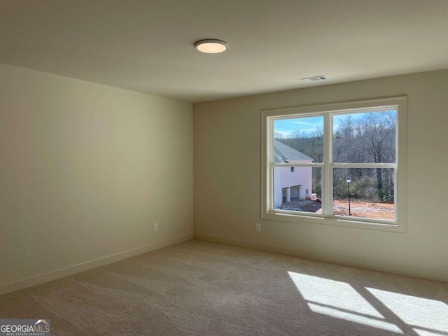empty room with visible vents, baseboards, and light colored carpet