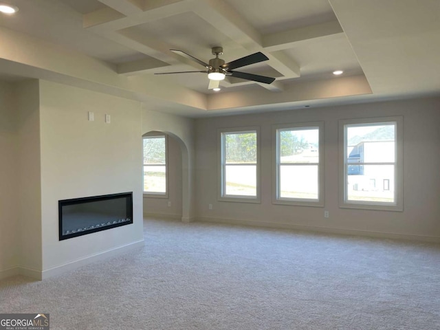unfurnished living room with coffered ceiling, baseboards, a glass covered fireplace, and a ceiling fan
