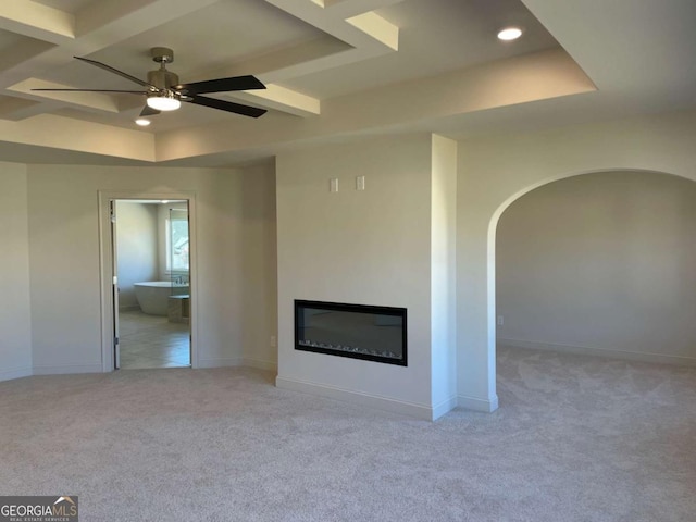 unfurnished living room featuring light carpet, baseboards, a ceiling fan, and a glass covered fireplace