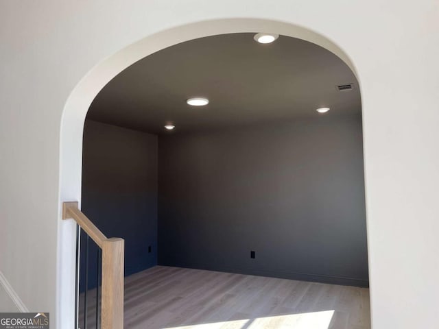 interior space featuring arched walkways, recessed lighting, baseboards, and light wood-style floors