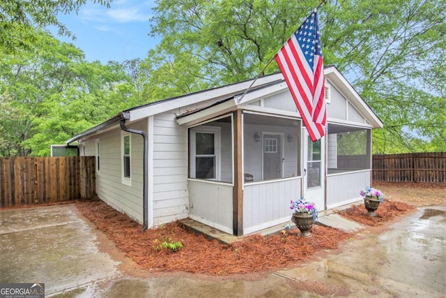 bungalow-style house featuring a sunroom and a fenced backyard