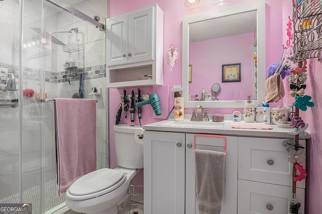 bathroom featuring toilet, vanity, and a shower stall