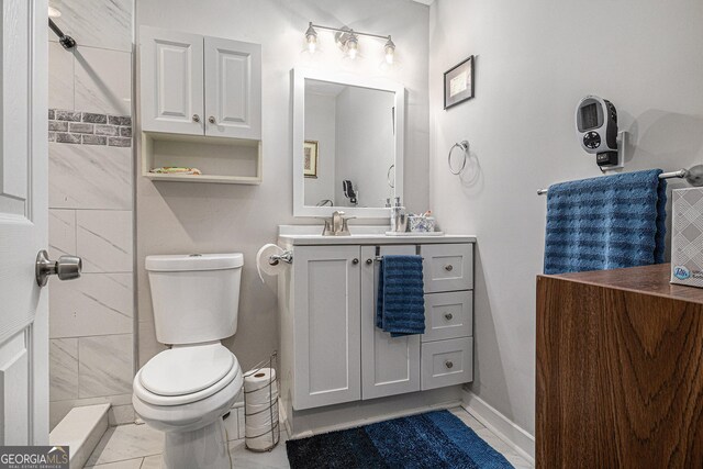 bathroom with toilet, vanity, baseboards, and marble finish flooring