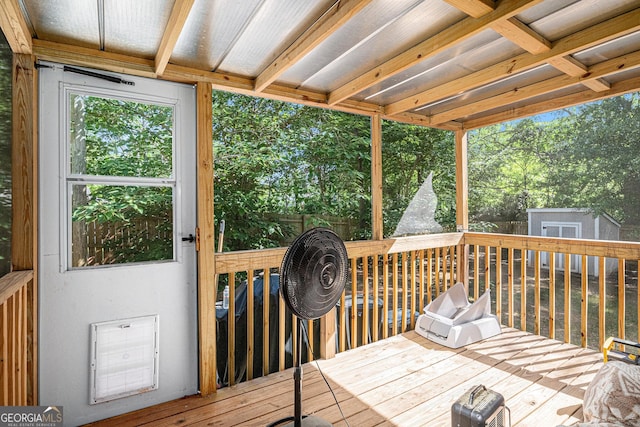 wooden deck featuring a storage unit, an outbuilding, view of wooded area, and fence