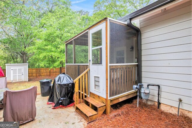 view of property exterior with a sunroom, a shed, an outdoor structure, and fence