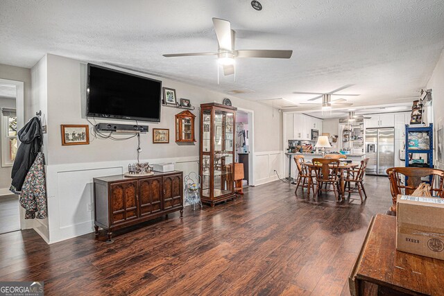 dining room featuring ceiling fan, a textured ceiling, wood finished floors, and a wainscoted wall