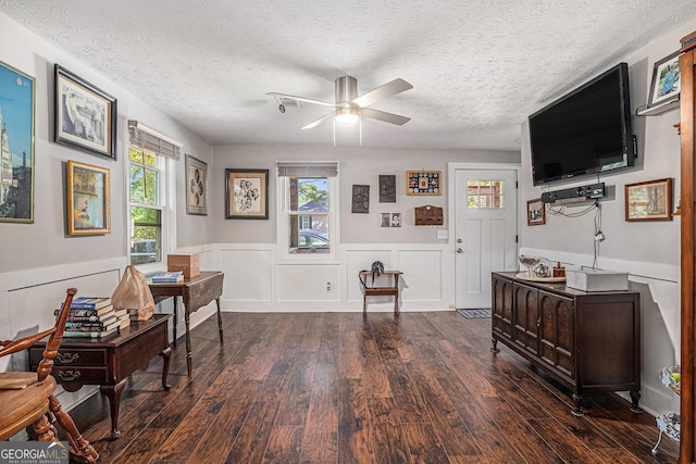 sitting room featuring ceiling fan, wood finished floors, a wainscoted wall, a textured ceiling, and a desk