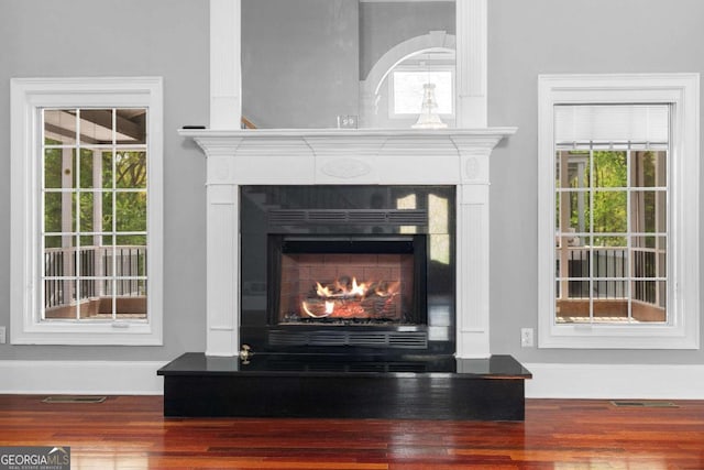 interior details featuring a warm lit fireplace, visible vents, baseboards, and wood finished floors