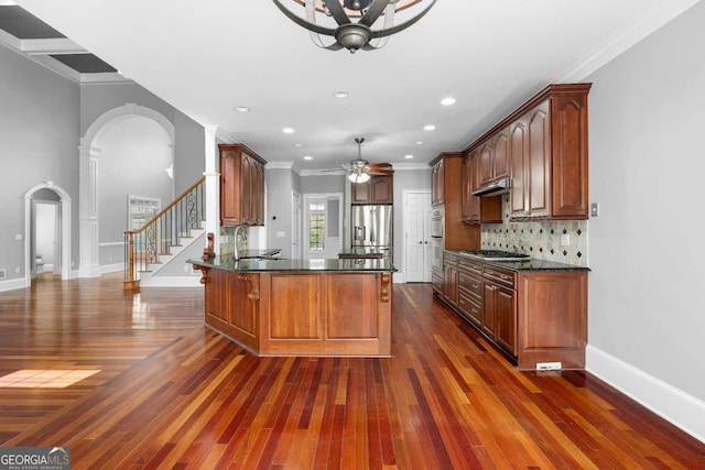 kitchen featuring stainless steel fridge with ice dispenser, arched walkways, a peninsula, gas cooktop, and a sink