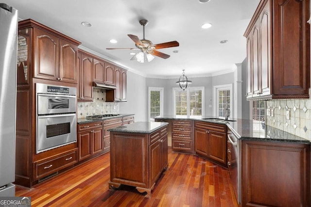 kitchen featuring a sink, ornamental molding, appliances with stainless steel finishes, a ceiling fan, and under cabinet range hood
