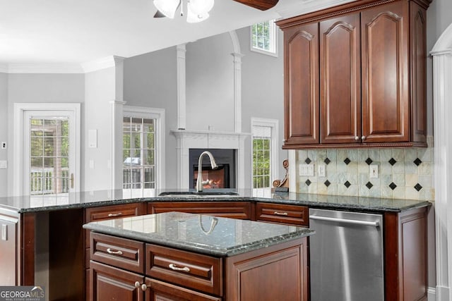 kitchen featuring stainless steel dishwasher, ornamental molding, a ceiling fan, dark stone countertops, and a sink