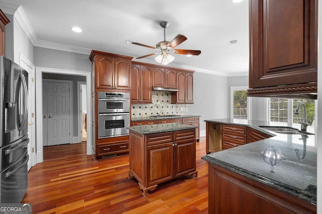 kitchen featuring a sink, ceiling fan, under cabinet range hood, crown molding, and stainless steel appliances