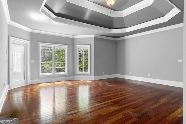 unfurnished room featuring ornamental molding, baseboards, a raised ceiling, and hardwood / wood-style flooring