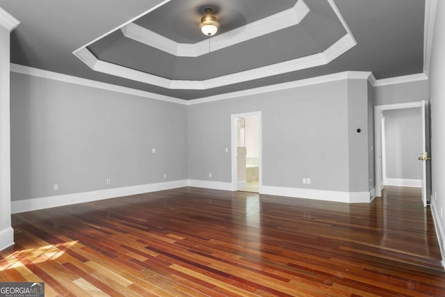 unfurnished room with crown molding, baseboards, a raised ceiling, and wood finished floors