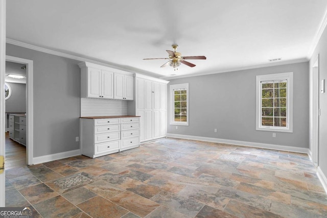 interior space with stone finish floor, ornamental molding, baseboards, and multiple windows