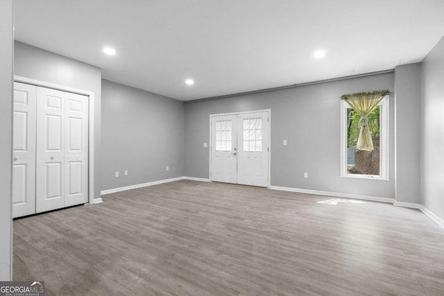 unfurnished living room featuring a wealth of natural light, recessed lighting, baseboards, and wood finished floors