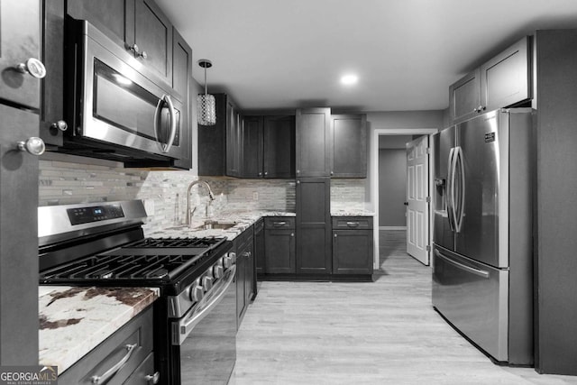 kitchen featuring a sink, decorative backsplash, appliances with stainless steel finishes, and light stone countertops