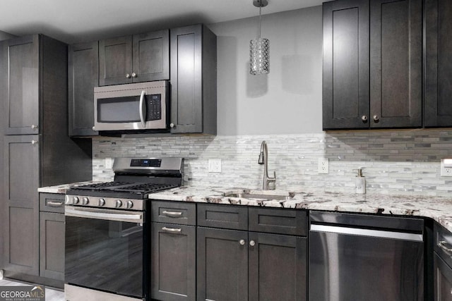kitchen featuring a sink, tasteful backsplash, appliances with stainless steel finishes, and light stone countertops