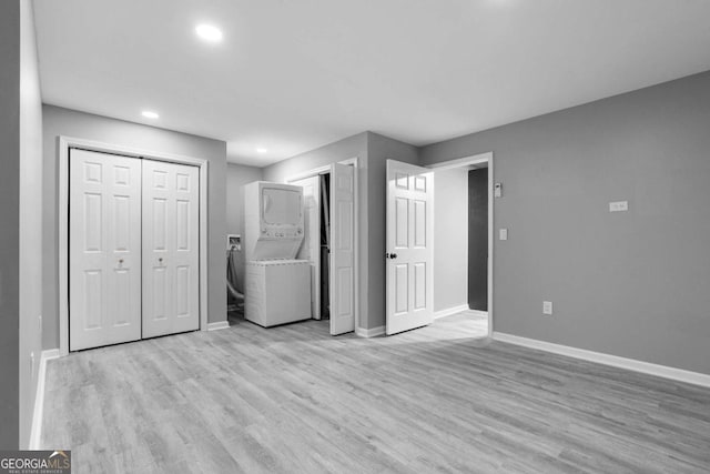 interior space with stacked washer and dryer, baseboards, light wood-type flooring, and recessed lighting