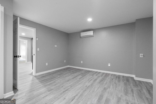 finished below grade area with recessed lighting, a wall mounted AC, baseboards, and wood finished floors
