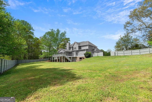 view of yard featuring a fenced backyard, a deck, and stairs