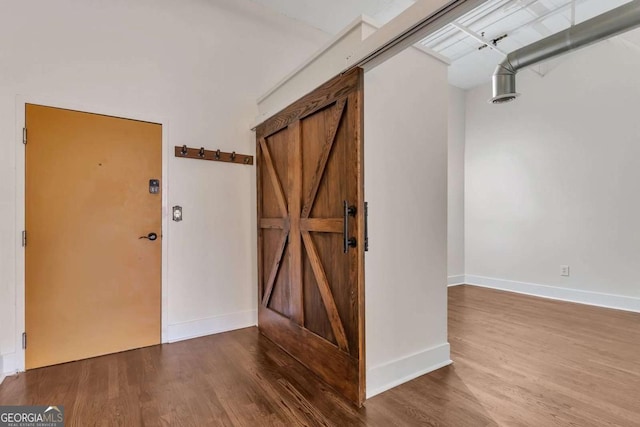 interior space with a barn door, baseboards, and wood finished floors