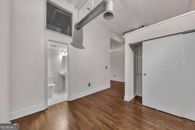 unfurnished bedroom with visible vents, baseboards, a closet, ensuite bath, and wood finished floors