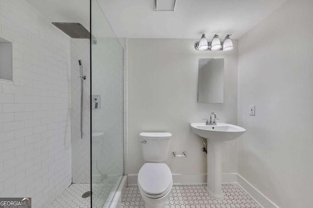 full bath with baseboards, a sink, toilet, tile patterned floors, and tiled shower