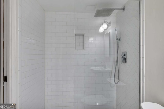 full bathroom with a tile shower and toilet