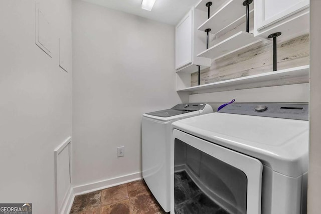 laundry area with baseboards, washing machine and clothes dryer, and cabinet space